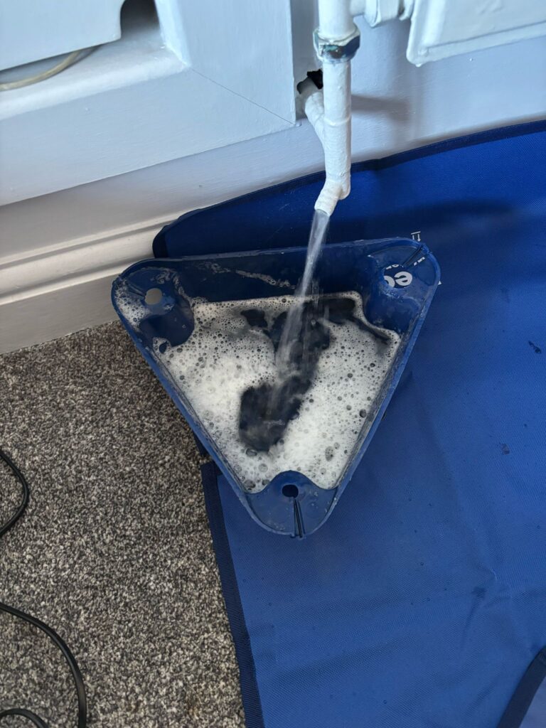 Water draining from heating pipework into a collection tray